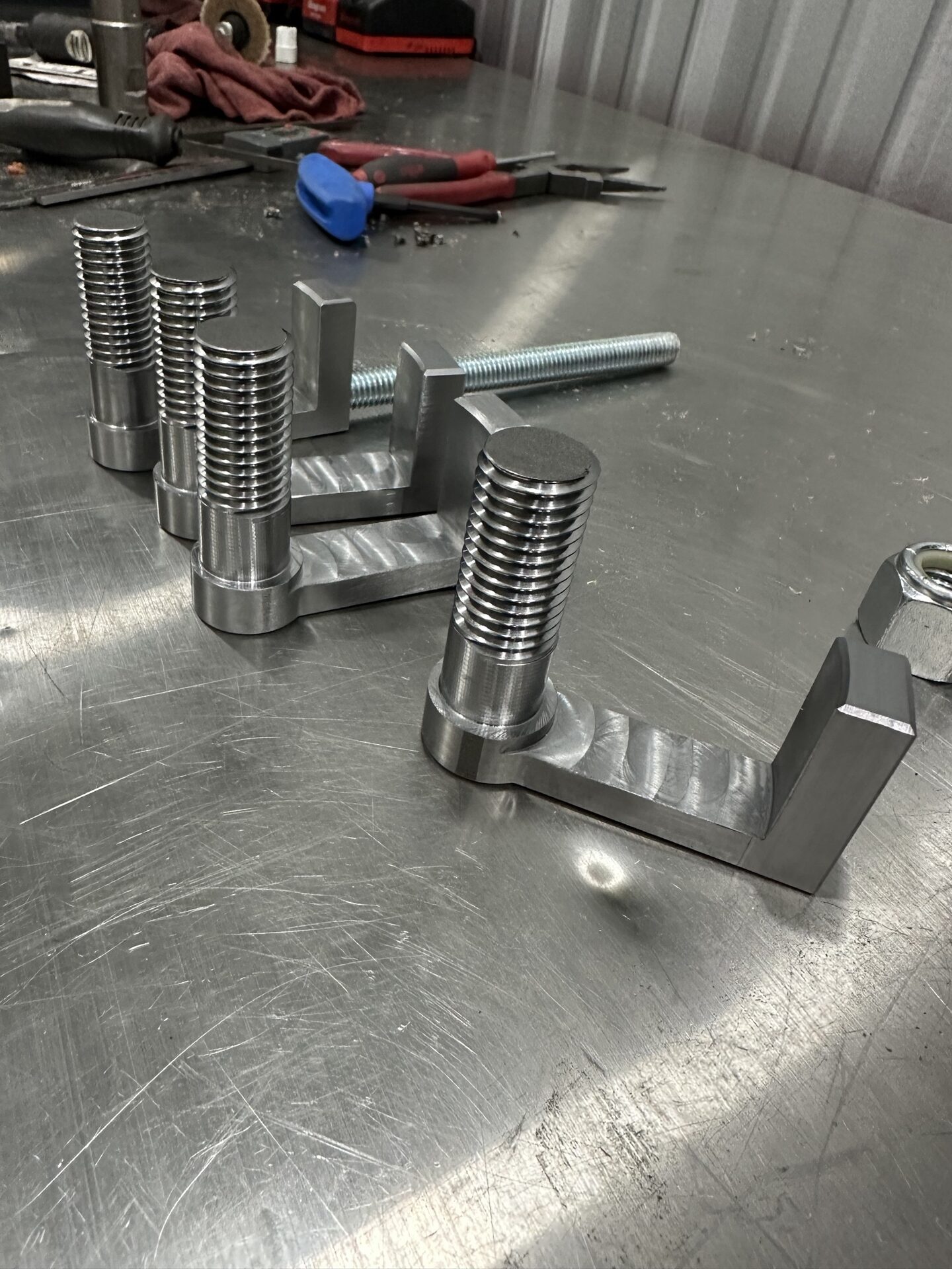 Freshly machined billet steel components on a shop table at Buffalo Tarp Co.